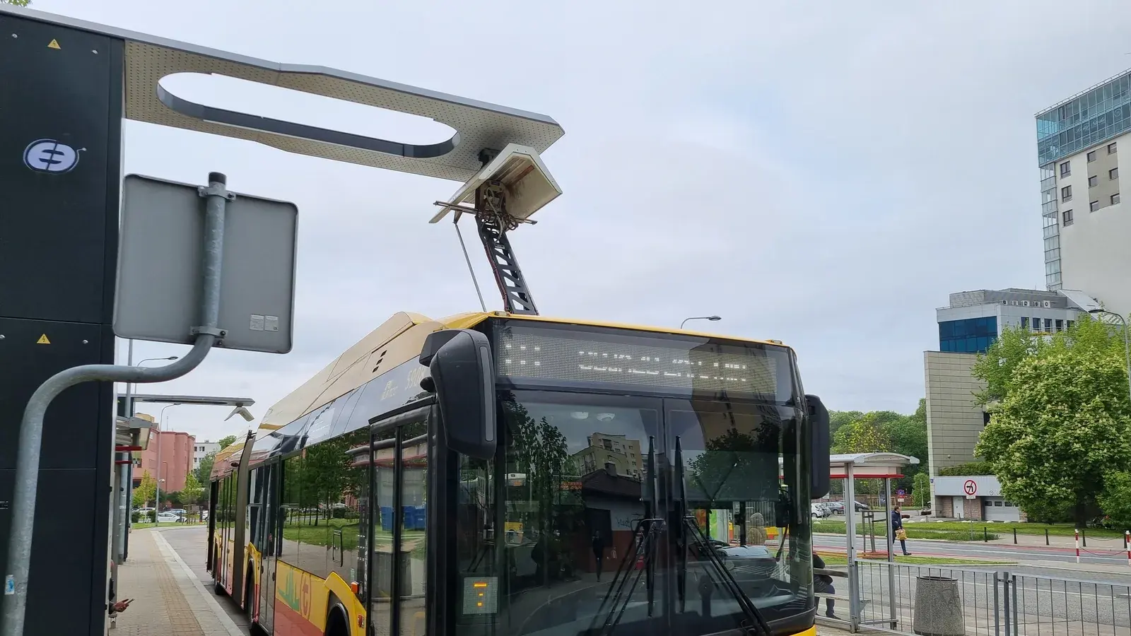 Gelb-roter Elektrobus in Warschau mit ausgefahrenem Dachpantograf unter einer Ladestation
