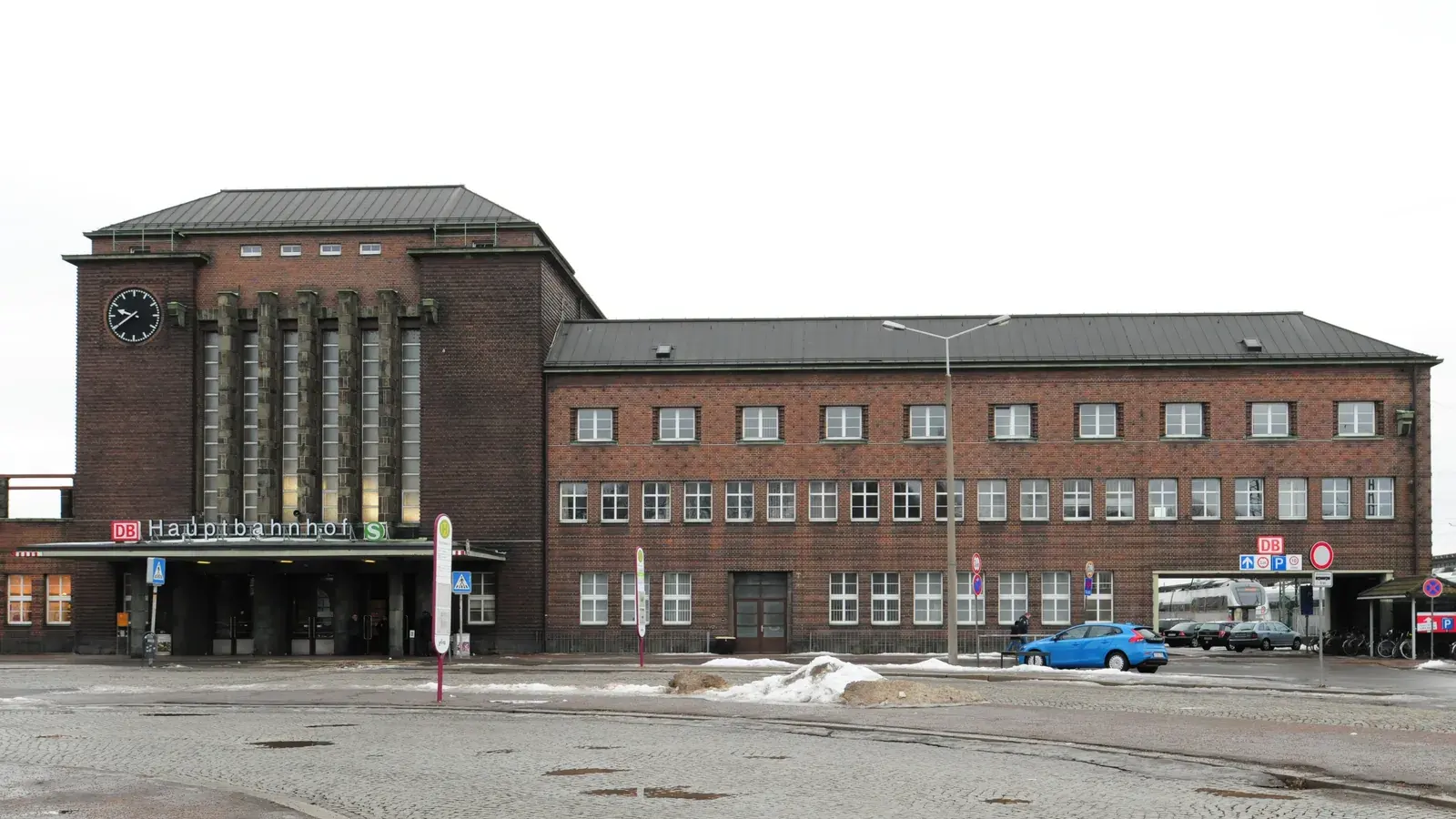 Archivaufnahme von 2017: Das Backsteingebäude des Zwickauer Hauptbahnhofs steht hinter dem gepflasterten Bahnhofsvorplatz; rechts ist unter einer Durchfahrt ein Reisebus zu sehen.