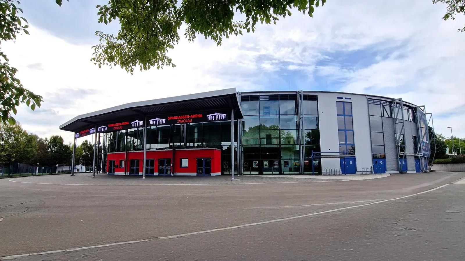 Archivaufnahme von 2025: Die verglaste und rot-graue Front der Sparkassen-Arena Zwickau steht hinter einem leeren Vorplatz; über den Eingängen leuchtet der Name der Arena.