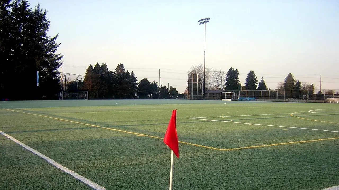 Rote Eckfahne an den weißen Linien eines leeren Fußballplatzes