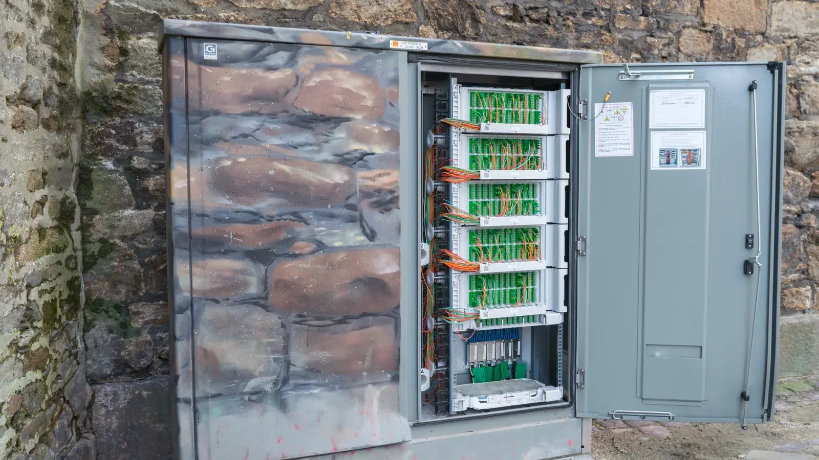 Beispielbild eines geöffneten Glasfaser-Straßenverteilers mit zahlreichen farbigen Leitungen in Saint-Malo
