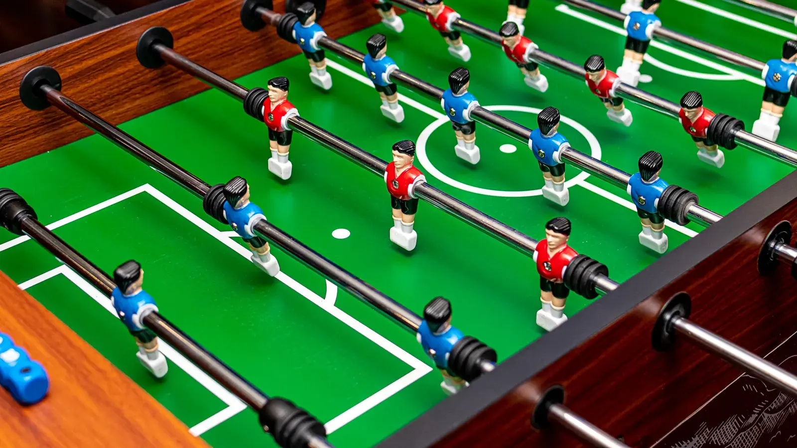 Symbolbild: Nahaufnahme eines Tischkickers mit roten und blauen Spielfiguren auf einem grünen Spielfeld. Das Bild zeigt weder das Jugendcafé Atlantis noch Eckersbach oder die angekündigte Wiederöffnung.