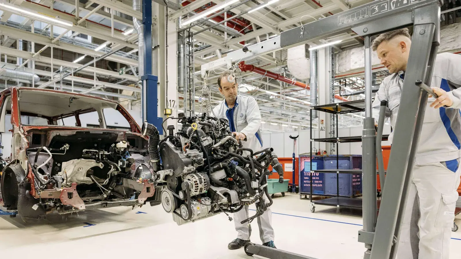 Ein Beschäftigter baut in einer Werkhalle den Motor aus einem alten Volkswagen T6 aus