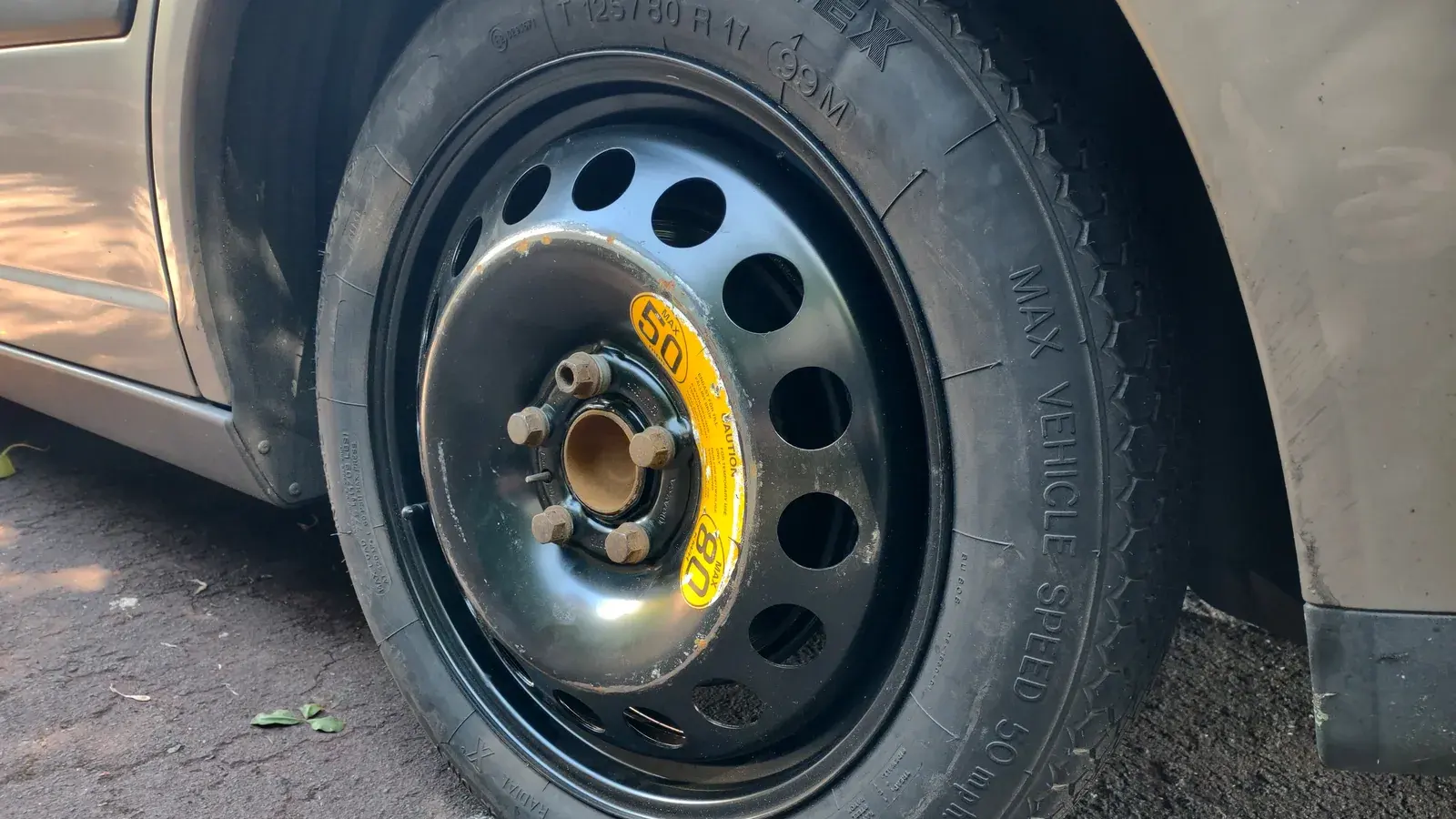 Symbolbild: Nahaufnahme eines montierten schwarzen Notrads an einem silberfarbenen Auto.