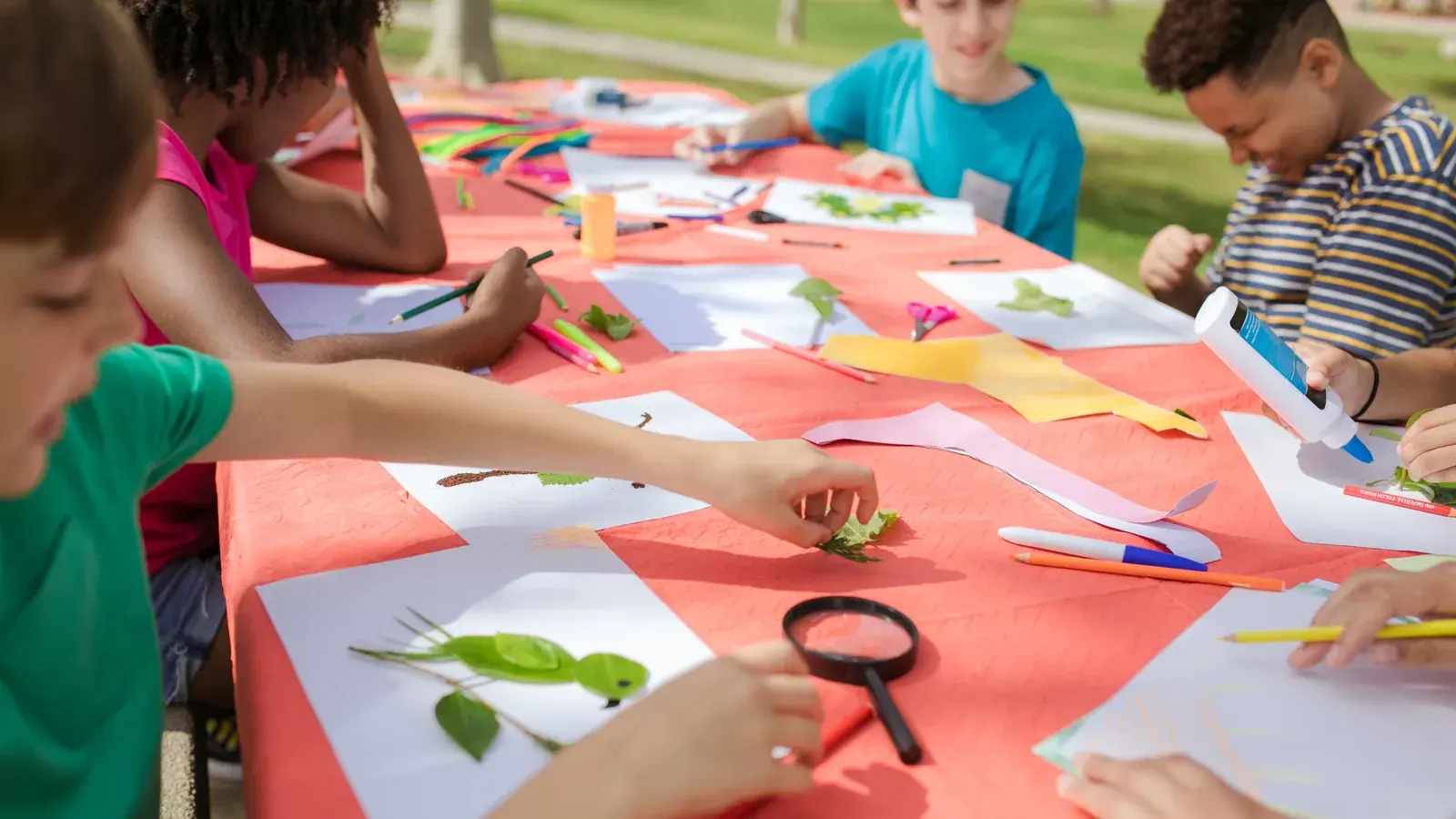 Symbolbild: Kinder gestalten im Freien an einem langen Tisch Bilder aus Papier, Blättern und Stiften. Die Aufnahme entstand nicht beim ZWIKKIFAXX in Zwickau.