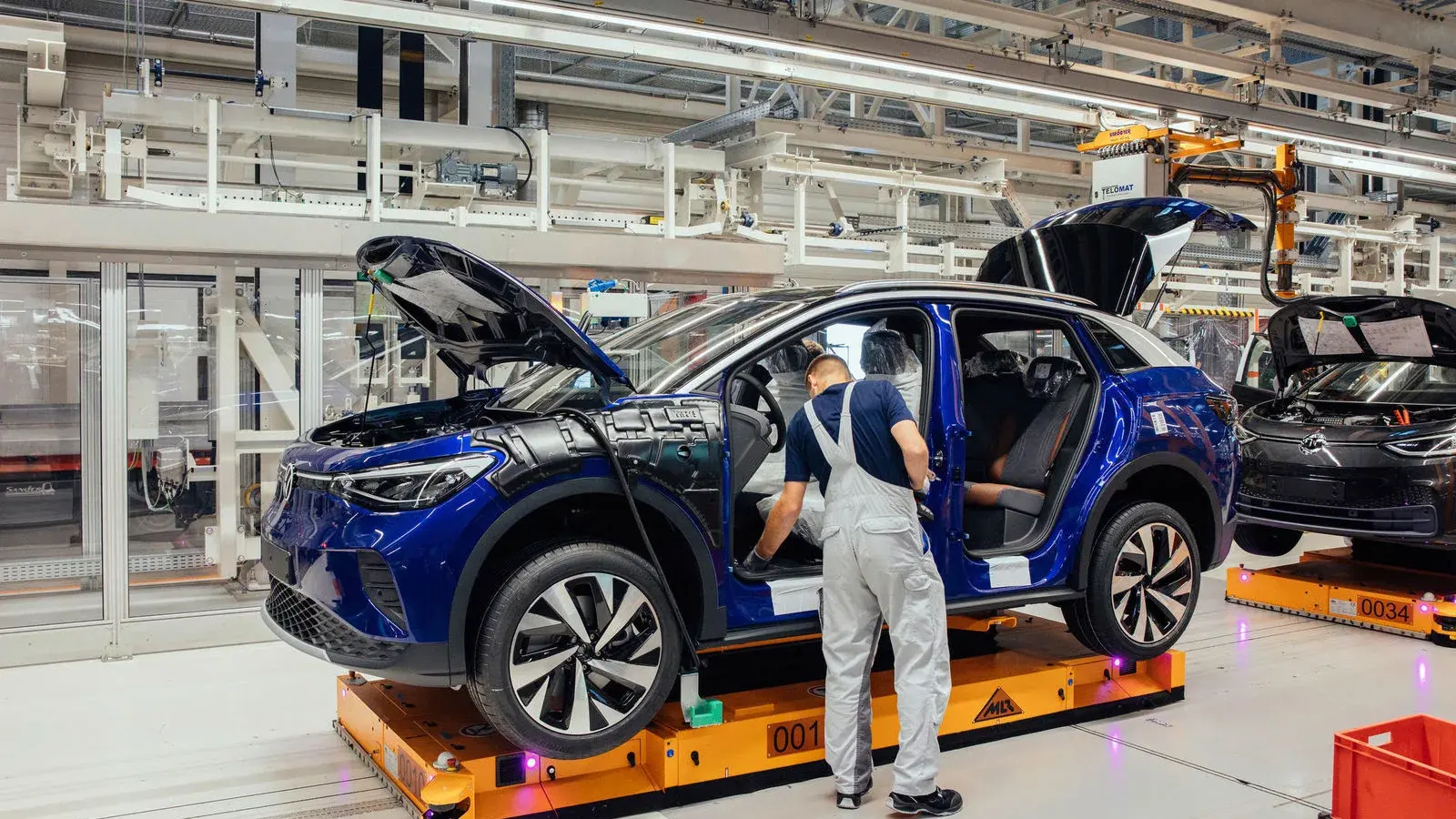 Ein Mitarbeiter arbeitet an einem blauen Volkswagen ID.4 auf der Montagelinie im Fahrzeugwerk Zwickau