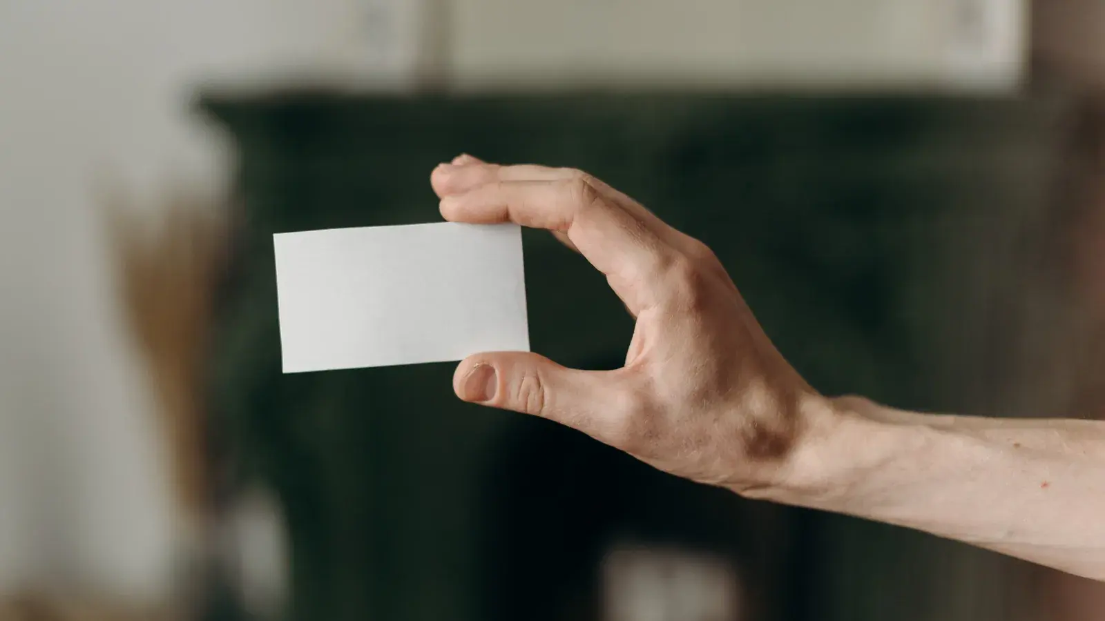 Symbolbild: Eine Hand hält eine vollständig weiße, unbedruckte Karte vor einem unscharfen dunklen Hintergrund.