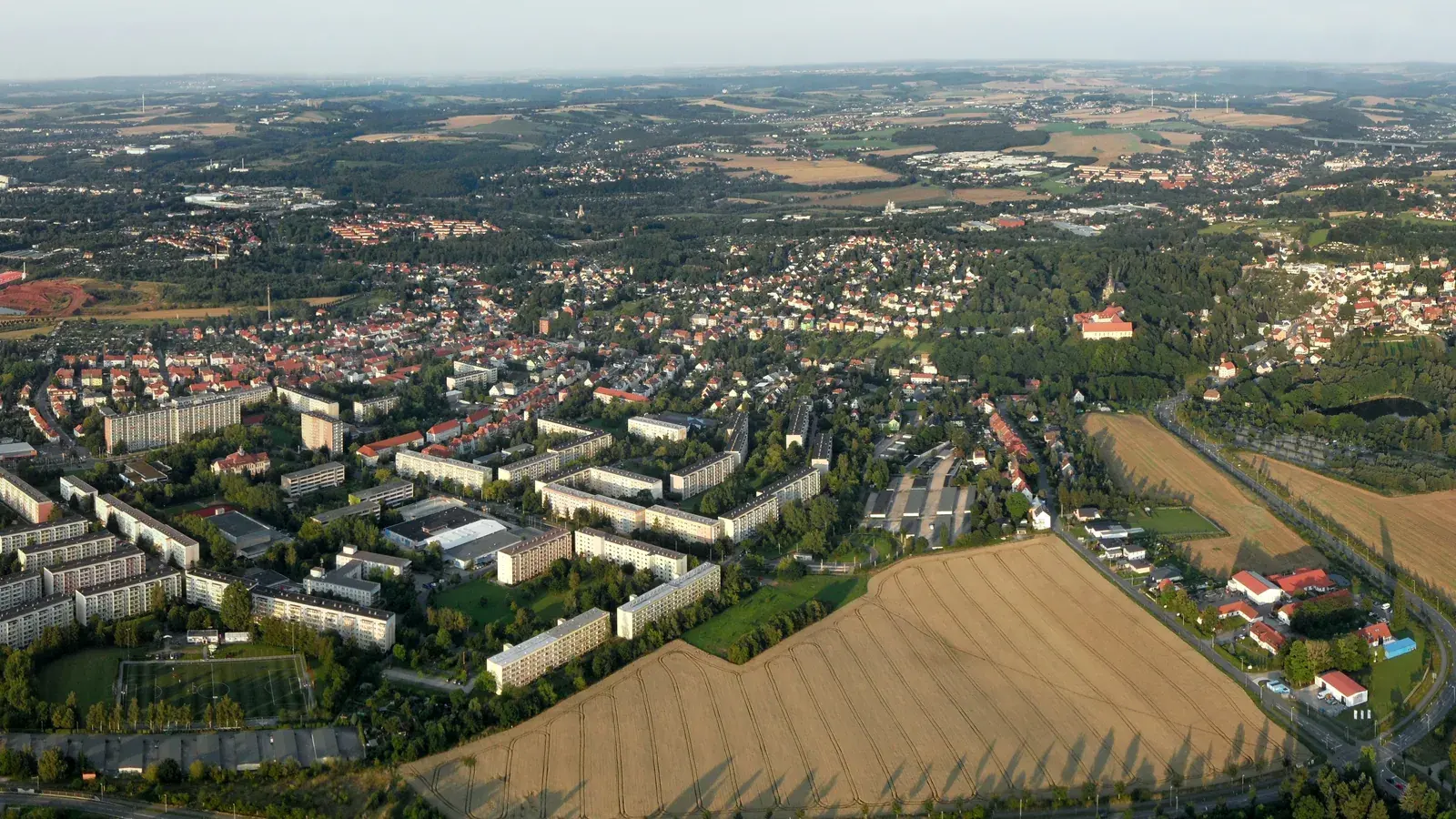 Breites Luftbild von Zwickau mit Wohngebieten, Gewerbeflächen, Feldern und Wald am Stadtrand.